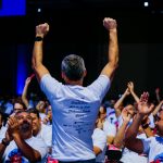 Excited spectators cheer for the speaker at a lively conference in Campinas, Brazil.